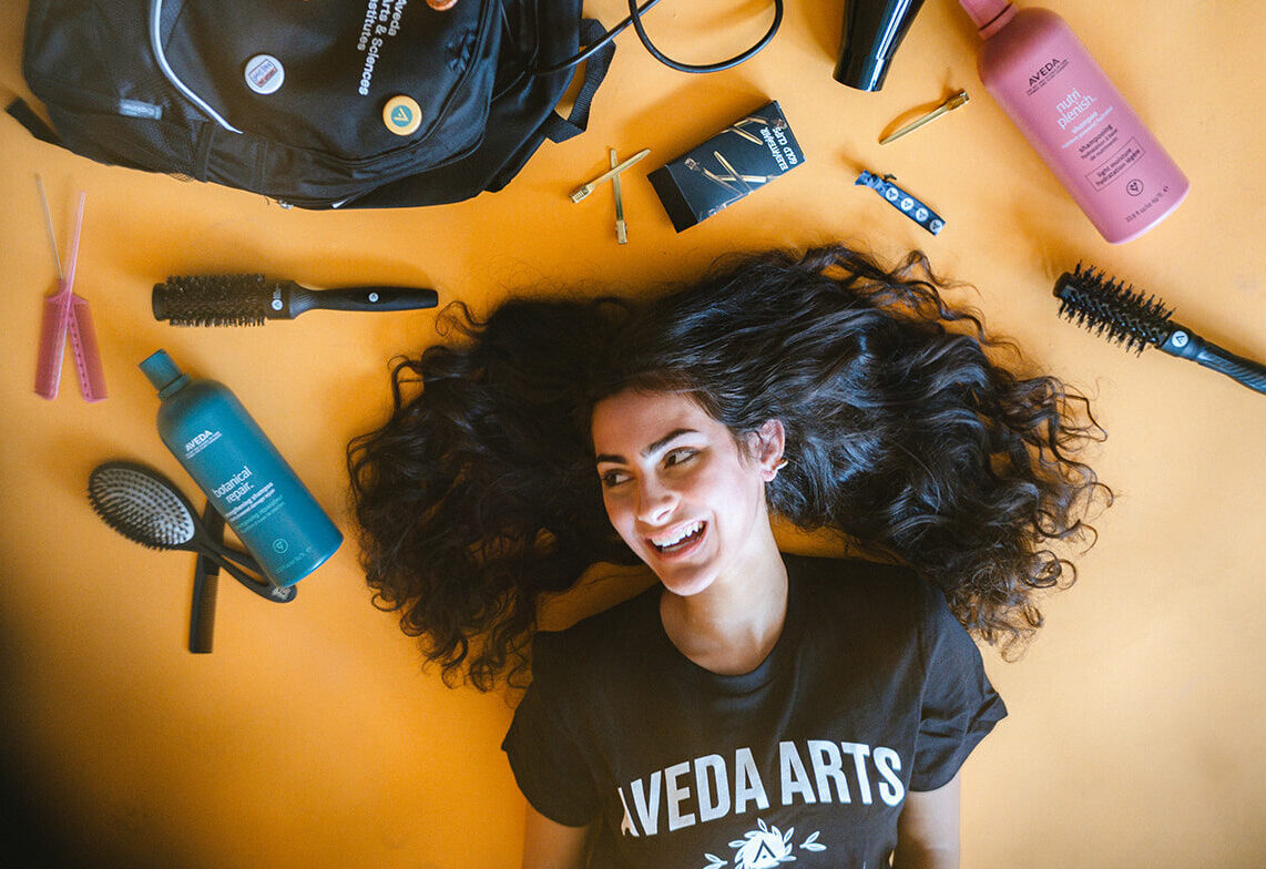 Aveda Arts Female Model On Ground With Student Kit For Aveda Arts Brand Shoot '24