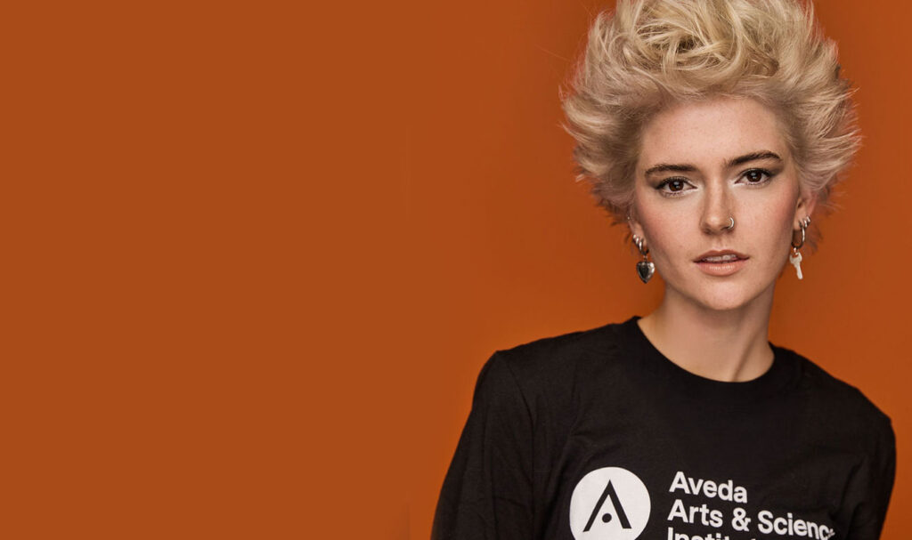Aveda Arts Model Wearing Logo Tshirt - Best Beauty School Near Me