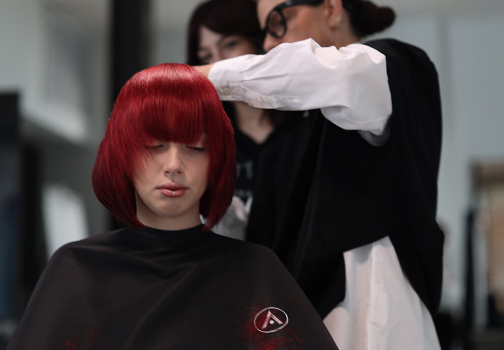 Educator Traci Sakosits teaching cosmetology students during an advanced haircutting education session at Aveda Arts New York.