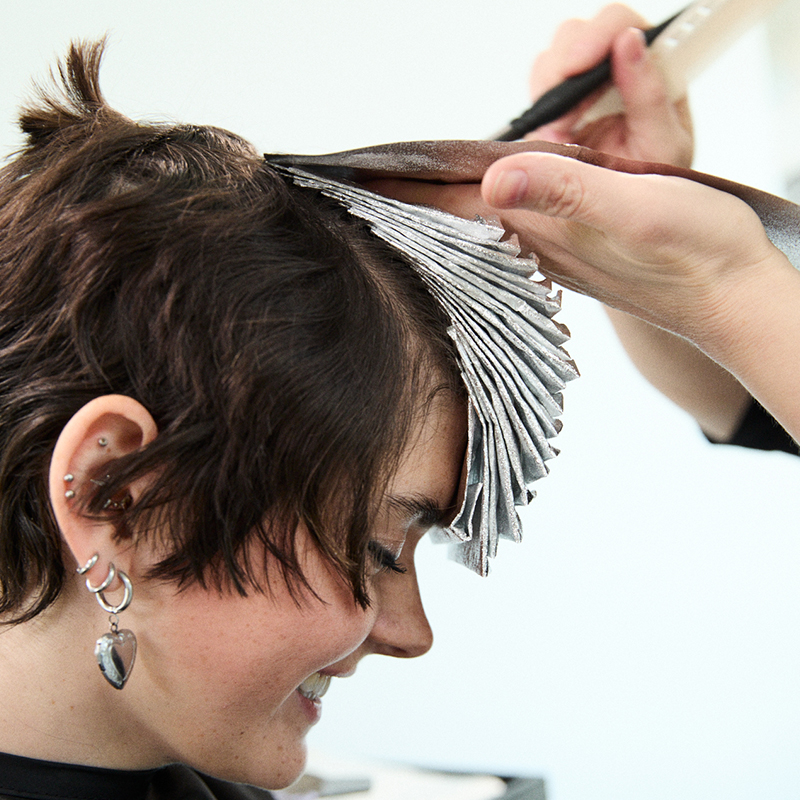 Beauty school student practicing hair color and styling techniques while developing creativity and real-world salon skills