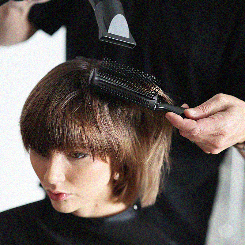 Cosmetology student styling hair on a guest during hands-on salon training.