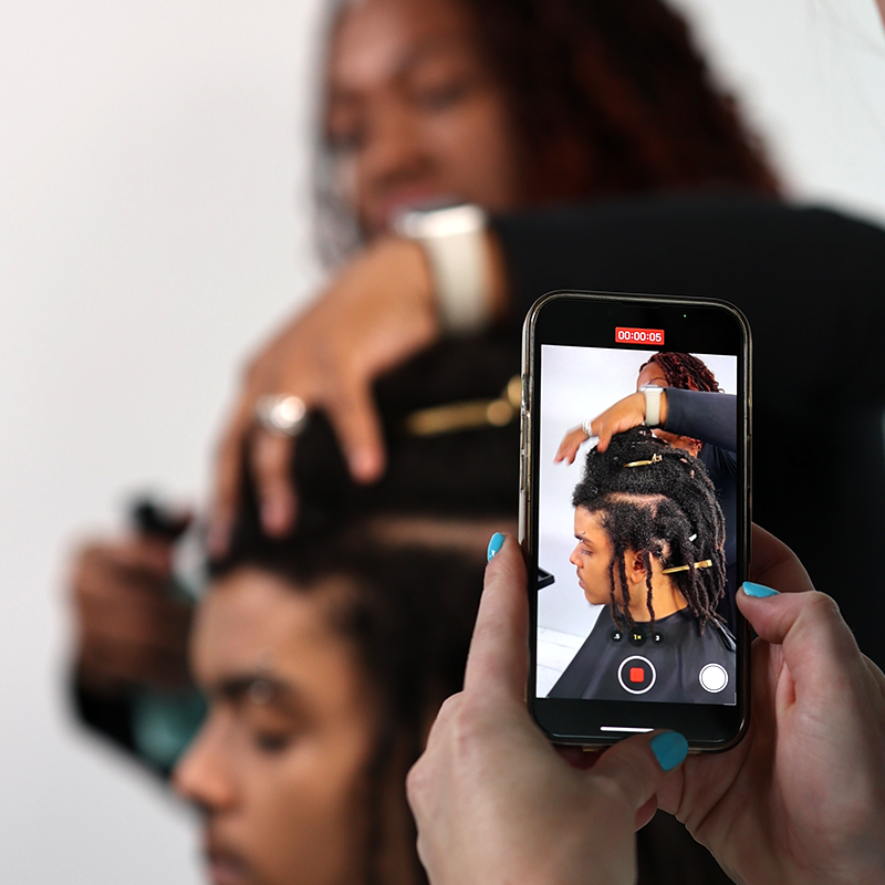 Cosmetology educator practicing styling techniques on textured hair to show beauty school students